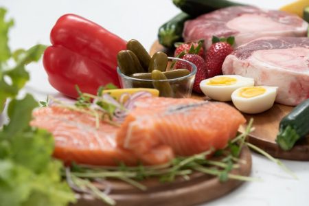 A vibrant assortment of fresh salmon, eggs, vegetables, and fruits arranged on a wooden platter.
